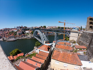 Fototapeta na wymiar The Dom Luis I Bridge over the Douro River and the colorful houses of Porto Ribeira, traditional facades, old multi-colored houses with red roof tiles on the embankment in the city of Porto, Portugal.