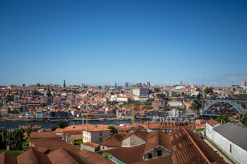The Dom Luis I Bridge over the Douro River and the colorful houses of Porto Ribeira, traditional facades, old multi-colored houses with red roof tiles on the embankment in the city of Porto, Portugal.