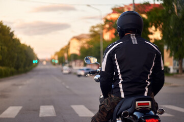 a motorcyclist stands at a traffic light