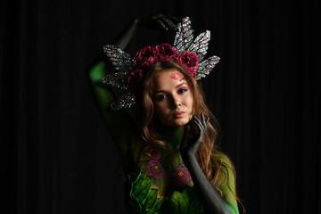 beautiful girl painted with green paint and flowers on her face and burgundy peonies in her body posing in different poses