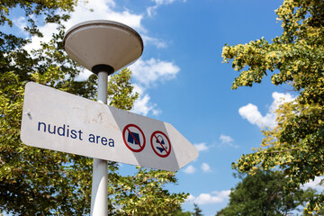 Information sign indicating designated area for nude sunbathing. Nudist area indication in beach club, summer vacation in clothing optional zone