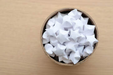 Fototapeta na wymiar Lucky paper stars in cardboard jar on wooden table