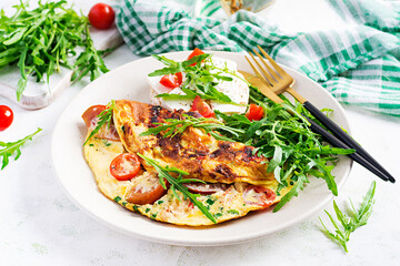 Omelette with tomatoes, cheese and green herbs on plate.  Frittata - italian omelet.