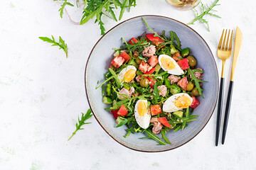 Healthy food. Tuna fish salad with eggs, cucumber, tomatoes, olives and arugula.  French cuisine. Top view, copy space, flat lay