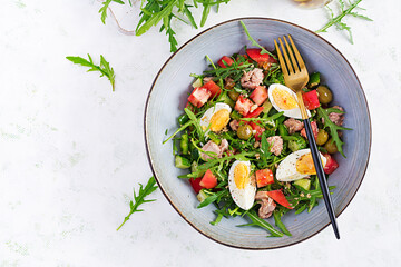Healthy food. Tuna fish salad with eggs, cucumber, tomatoes, olives and arugula.  French cuisine. Top view, copy space, flat lay