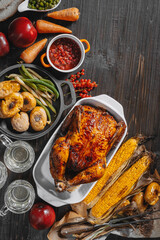 Thanksgiving celebration concept, baked turkey with vegetables on a table with corn, green peas, ripe apples and other vegetables. autumn harvest