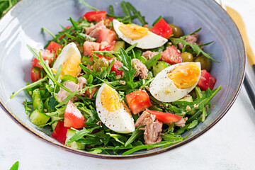 Healthy food. Tuna fish salad with eggs, cucumber, tomatoes, olives and arugula.  French cuisine.