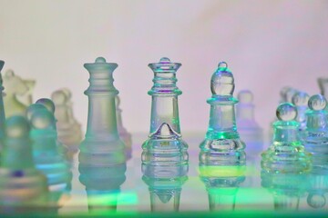 glass chess with green lighting and white background with chess coins like queens, soldiers, bishop.