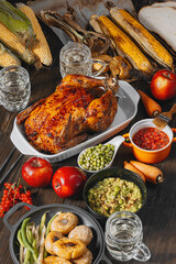 Thanksgiving celebration concept, baked turkey with vegetables on a table with corn, green peas, ripe apples and other vegetables. autumn harvest