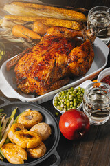 Thanksgiving celebration concept, baked turkey with vegetables on a table with corn, green peas, ripe apples and other vegetables. autumn harvest