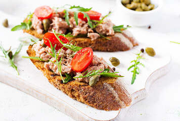 Toasts with tuna. Italian bruschetta sandwiches with canned tuna, tomatoes and capers.