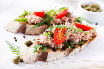 Toasts with tuna. Italian bruschetta sandwiches with canned tuna, tomatoes and capers.
