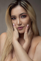 Naklejka premium portrait of a beautiful woman with blond hair and hands on her neck, make up, studio