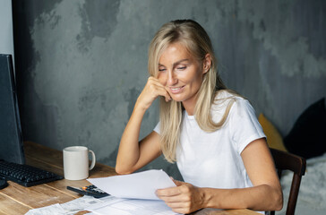 Young presentable white business woman reads documents and smiles.