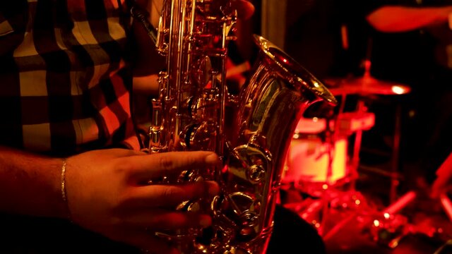 Saxophonist playing jazz music on a night club with other musical instruments in background