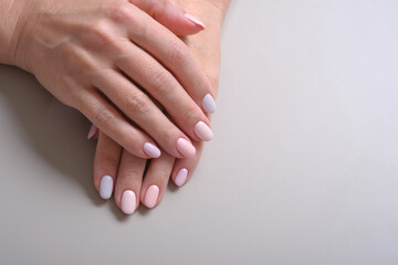 Stylish trendy manicure nail adult woman hands on a grey background, top view. Selective focus