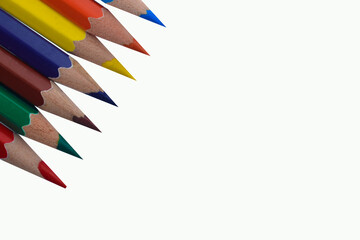 A Line of seven different colored wood pencil crayon places on a white paper