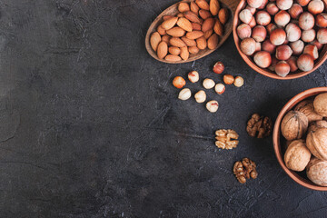 Fototapeta na wymiar Walnut, hazelnuts and almonds in a spoon against a dark background