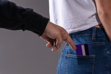 Close-up: a man's hand pulls out a credit plastic card from the back pocket of women's jeans. Theft. Financial crisis.