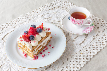 Sweet cake with berries on the plate with cup of tea