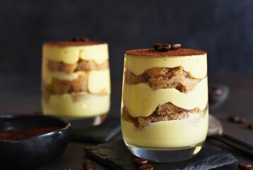 Classic tiramisu in a glass on a dark background.