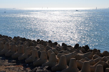 Obraz premium view of wave breakers from above with sun reflecting on calm water