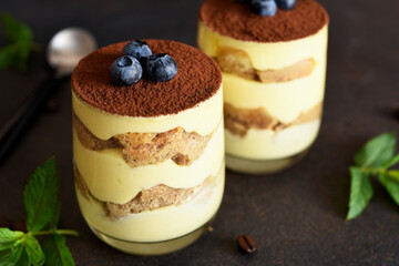 Classic tiramisu in a glass on a dark background.