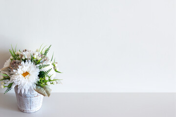 Wall mockup with pot of flowers on white surface. Copy space.