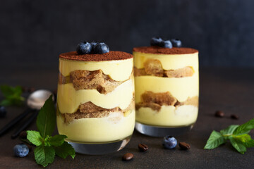 Classic tiramisu in a glass on a dark background.