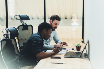 African american student with qualified tutor discussing studying project during private lesson sitting at laptop computer with wireless internet.Two colleagues teamworking on solution in office