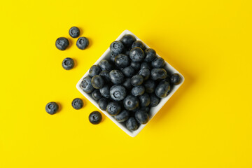 Square bowl with blueberry on yellow background