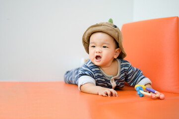 Naklejka premium Funny 8 months baby boy wearing a cap sitting on sofa.