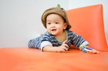 Funny 8 months baby boy wearing a cap sitting on sofa.