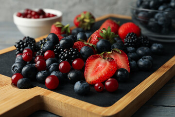 Board with fresh berries on wooden background, close up