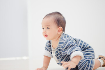 Smiling crawling asian baby boy at home on floor with white background.