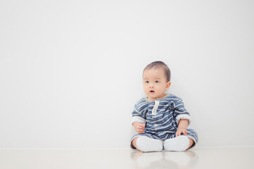 Smiling sitting asian baby boy at home on floor with white background.