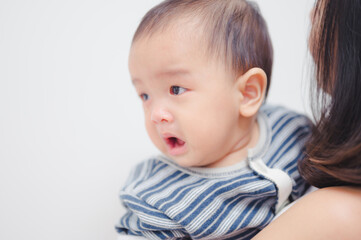 Naklejka premium Portrait of 8 months baby boy crying with mother while she holds him and tries to comfort him.