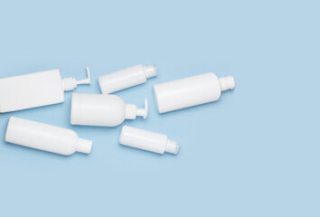 A set of white cosmetic cans for face and body care are in a basket on a blue background. Purchase of cosmetics and hygiene products, home shopping