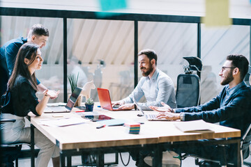 Young team of professionals discussing ideas and effective solutions for improving work process at meeting table during brainstorming in modern office.Employees collaborating on business project
