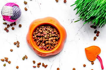 dry cat food in bowl on stone background top view