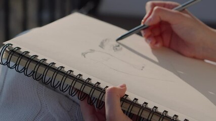 Female artist drawing portrait in sketchbook