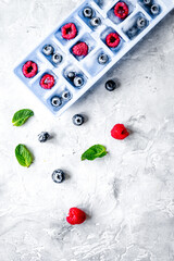 blueberry and raspberry in ice tray on stone background top view mock-up