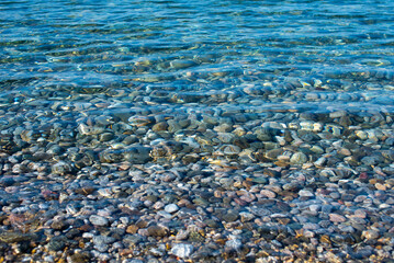 Colorful sea stones. Sea pebble / stones background/ beach rocks. Colorful summer background. Top view. Pebble in the blue water. Wet beautiful stones. Summer background. Copy space.