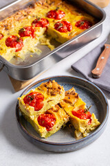 Vegetable clafoutis on gray plate on concrete background, savory pie with cabbage and whole cherry tomatoes. Vegetarian cuisine.
