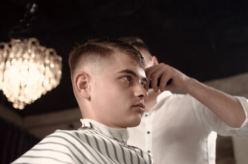 Men's hairstyling and hair cutting in a barber shop or hair salon.
