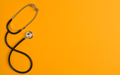 Covid-19 Coronavirus concept. Stethoscope medicine accessory, orange background with copy space....