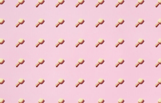 From above of pattern of popsicles placed in rows on pink background in studio