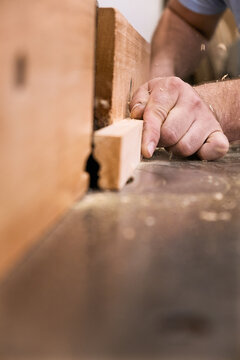 Low angle of closeup unrecognizable carpentry master milling timber using modern electric machine in light contemporary workshop