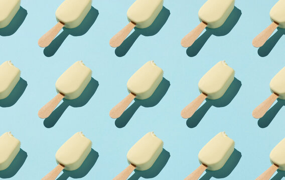From above of pattern of popsicles placed in rows on blue background in studio