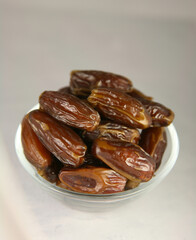 Juicy ripe dates in a glass bowl on a gray table